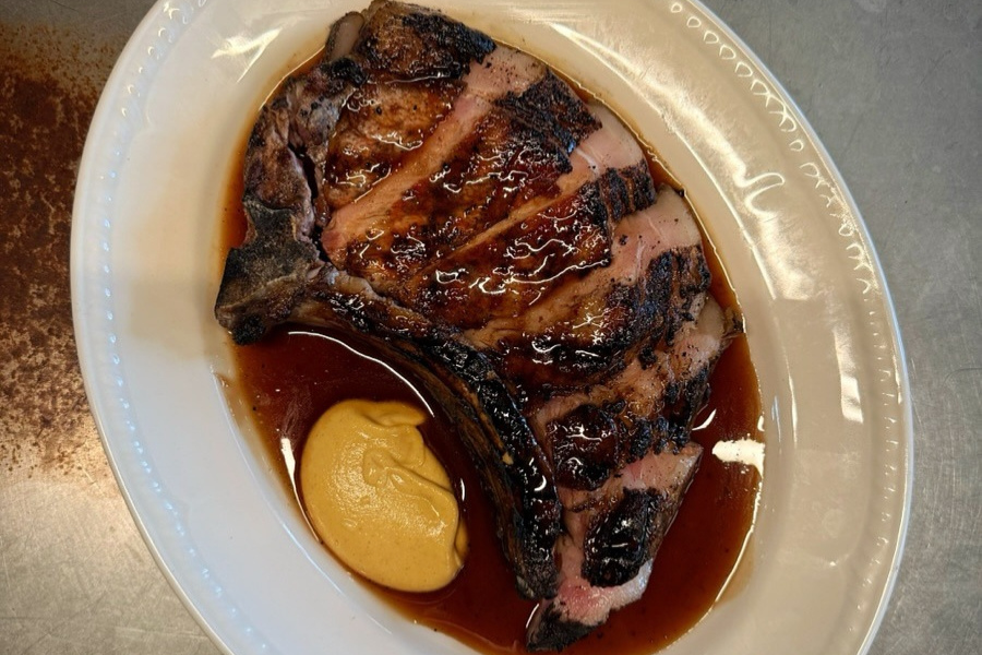 A salt-aged pork chop in dark jus on a plate at Raymond’s in Nottingham